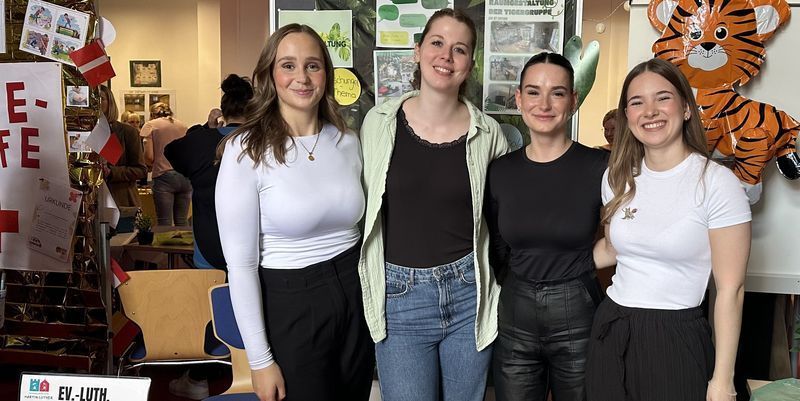 Vier junge Erwachsene an einem Informationsstand beim Markt der Möglichkeiten am Diakonie-Kolleg