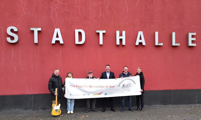 Gruppe vor Gifhorner Stadthalle hält Banner Ein Fest für Menschen in Not